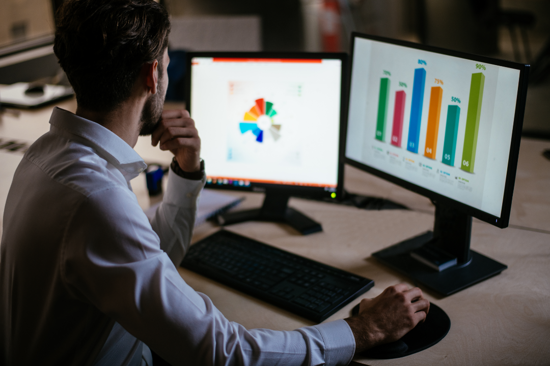 A dual-monitor setup displaying keyword research, search rankings, and analytics on a digital marketing workspace.