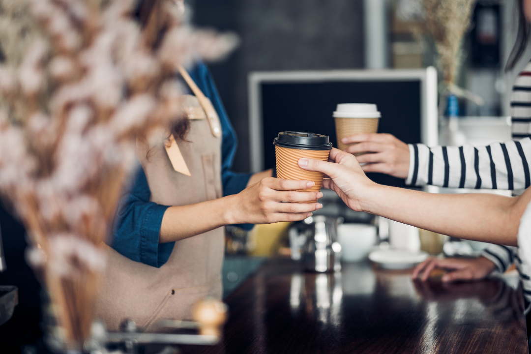 A vibrant coffee shop with customers enjoying their time and leaving reviews on their smartphones, symbolizing community and online interaction.