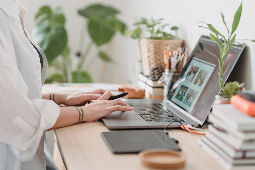 A photo of a content creator sitting at a stylish, well-lit desk, typing on a laptop. The image captures the essence of hands-on experience and first-person involvement in content production—crucial for the Experience factor in E-E-A-T.